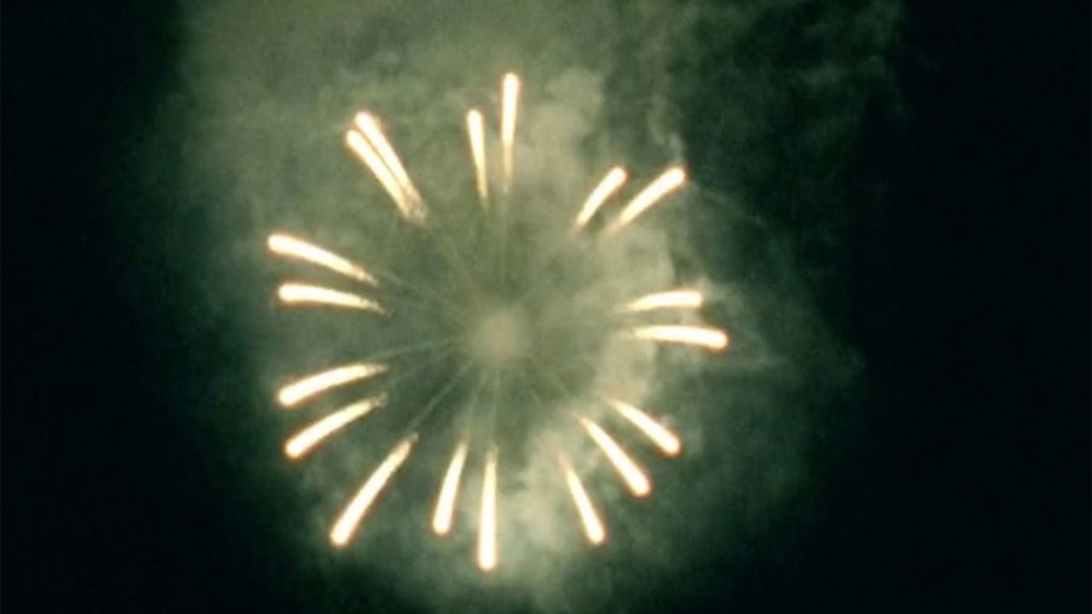 A still frame from Atomic Garden, a film by Ana Vaz. The image is of a firework exploding in the sky in a circular pattern.